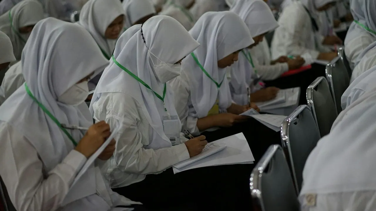 Peserta berhijab mencatat materi di ruang kelas