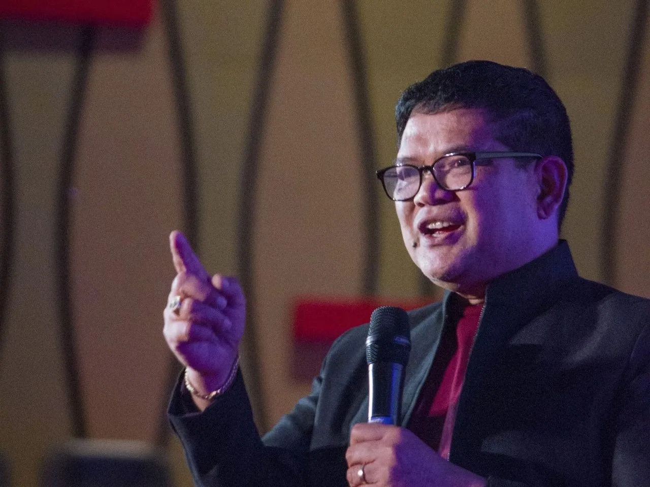 Pemateri menyampaikan materi dengan mikrofon di panggung