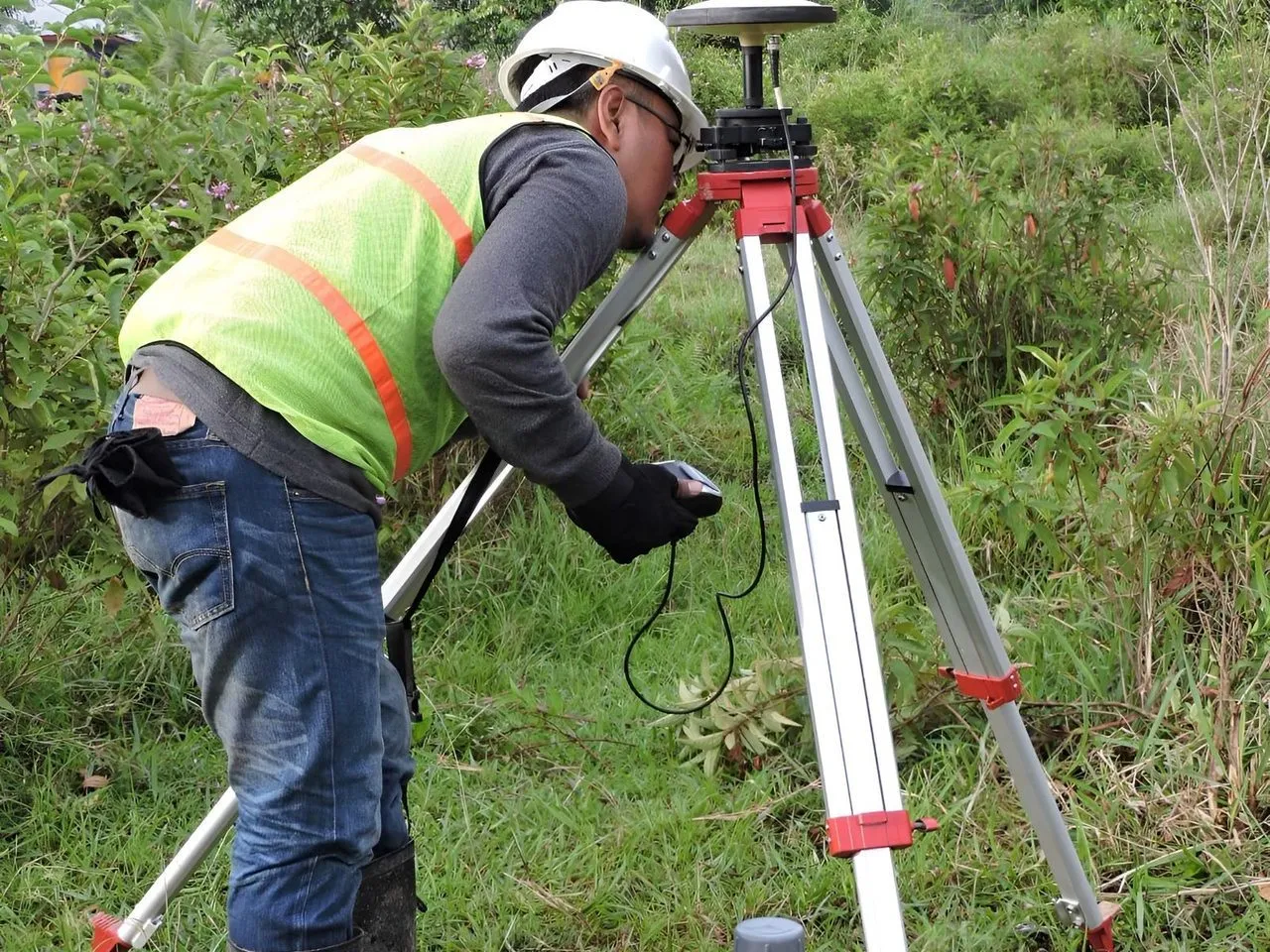 Juru ukur memakai alat survei di lapangan