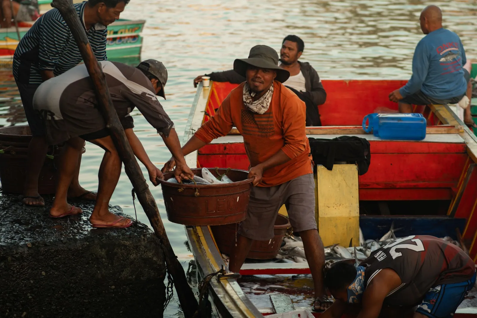 Nelayan menurunkan hasil tangkapan ikan di dermaga