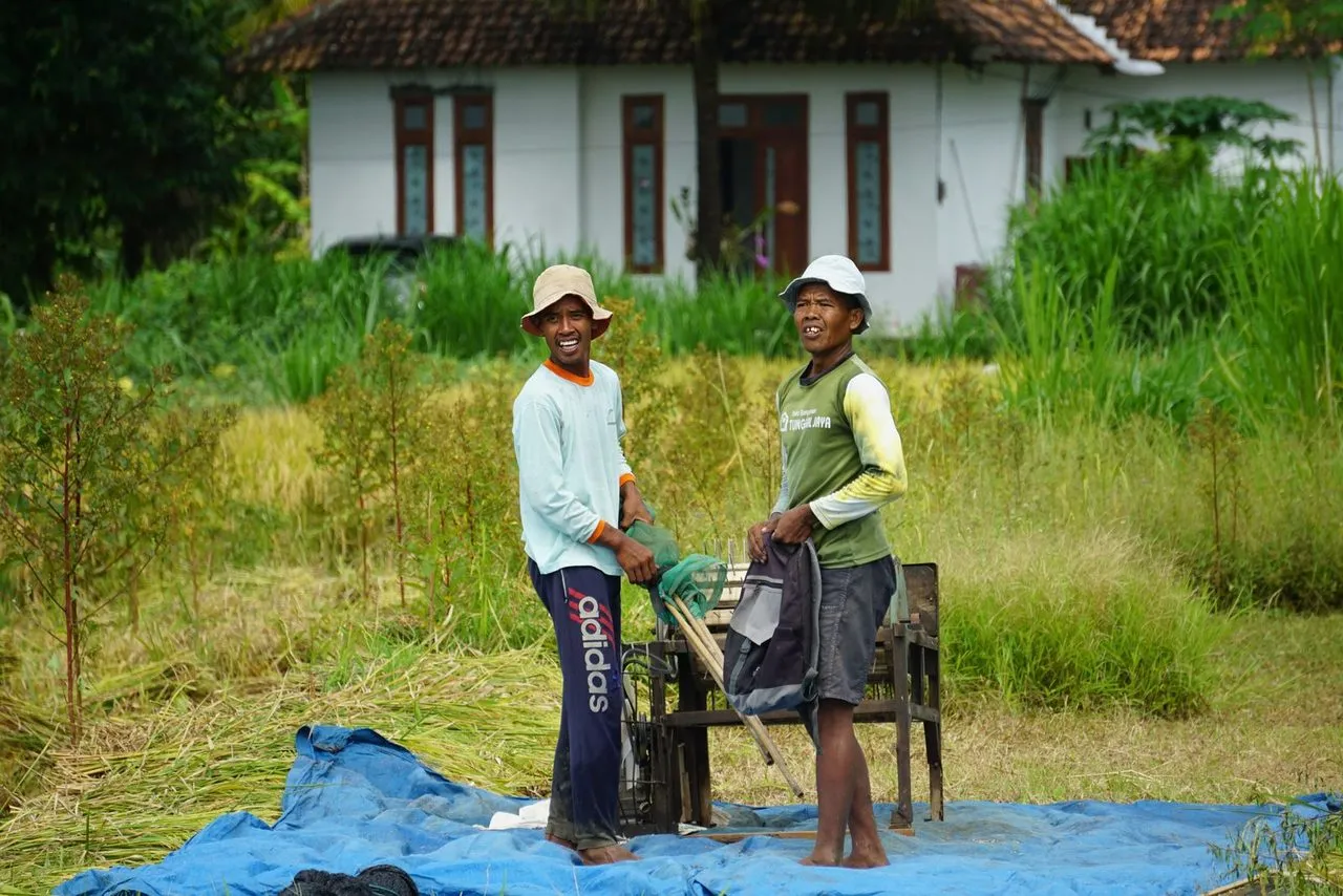 Dua petani tersenyum bekerja di ladang
