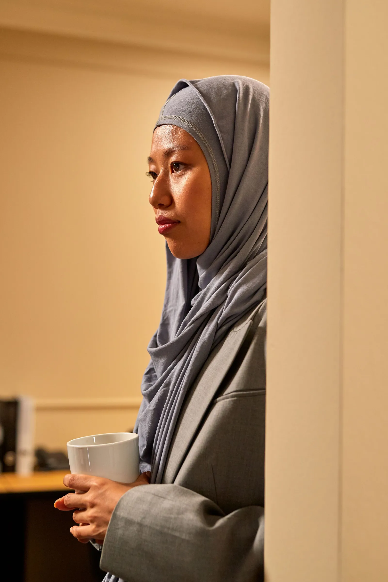 Perempuan berhijab berdiri di ruang kantor