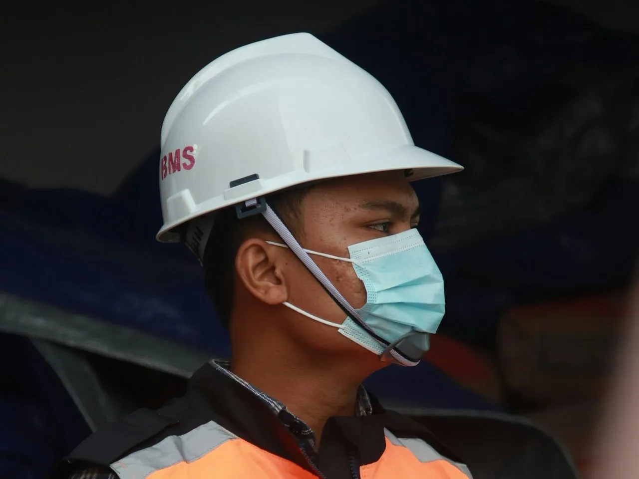 Pekerja berhelm putih dan rompi keselamatan