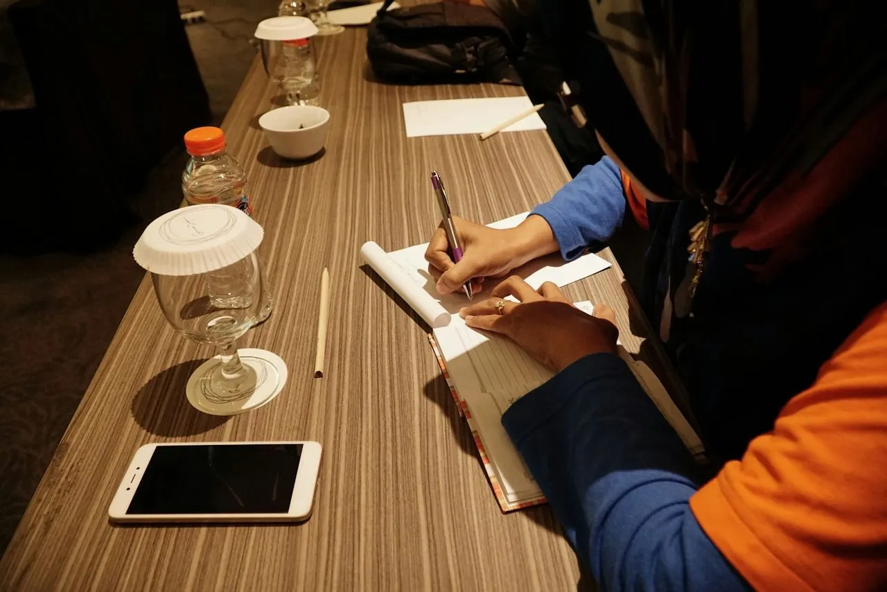 Peserta mencatat materi di meja pelatihan