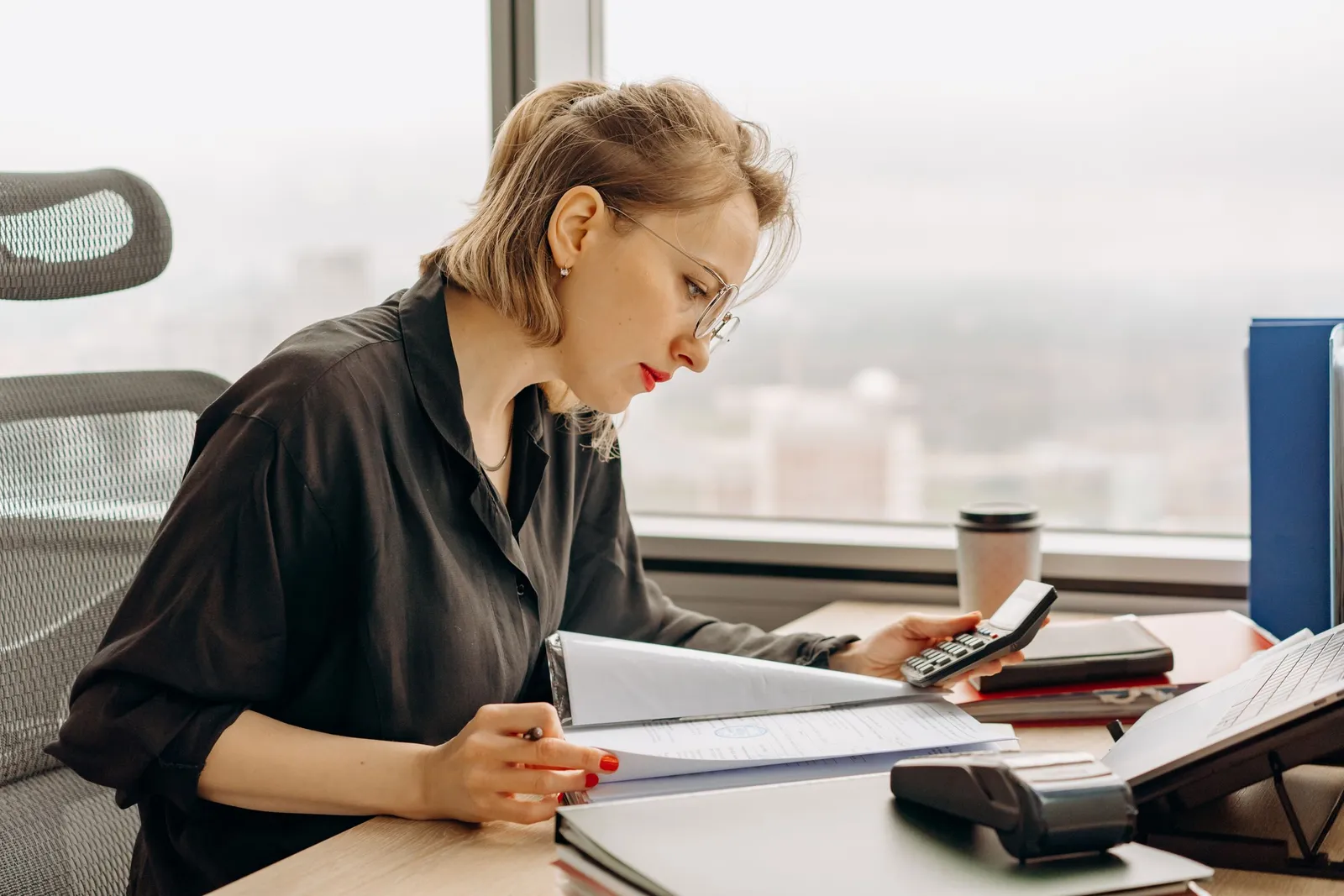 Perempuan menghitung dokumen keuangan di meja kantor