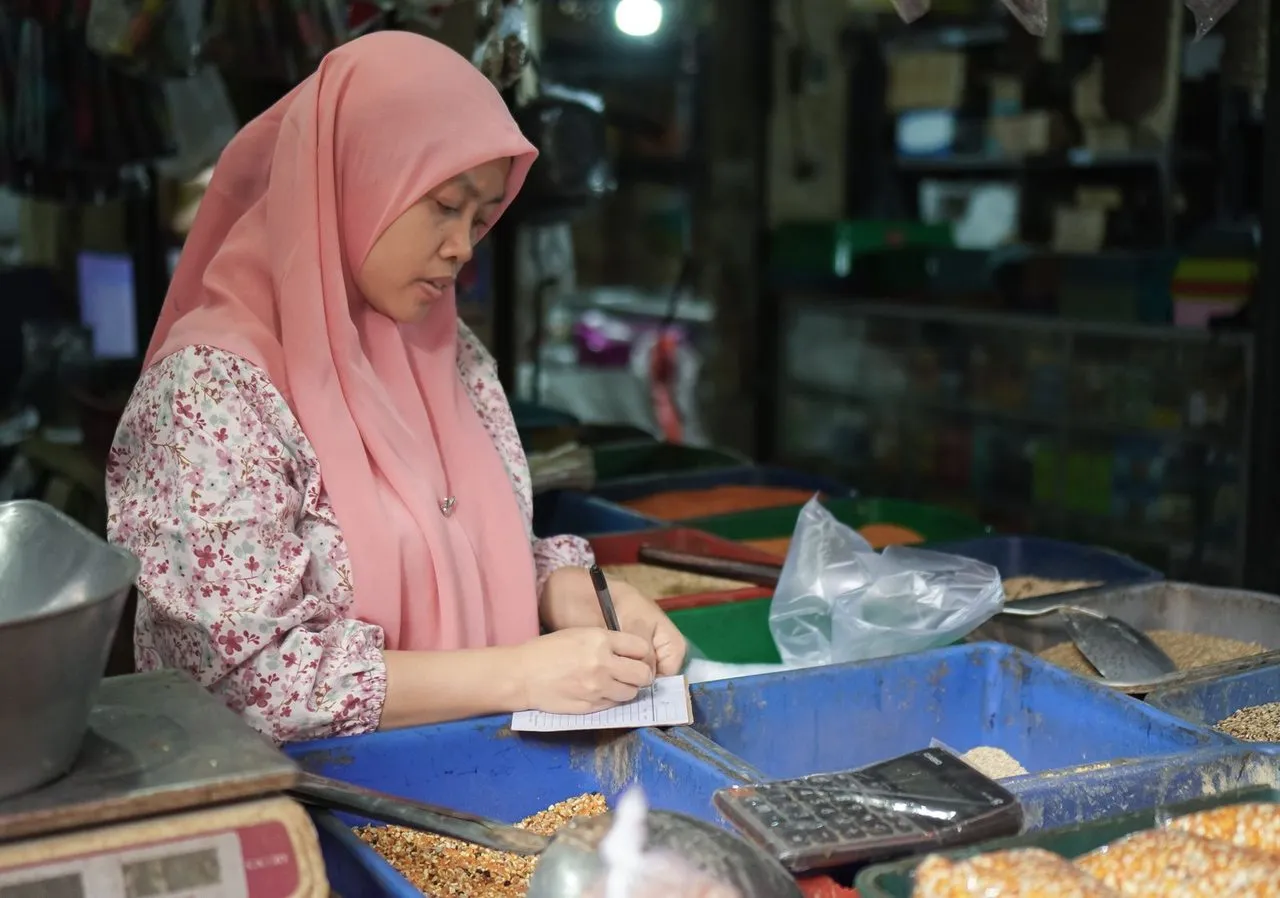 Pedagang berhijab menghitung penjualan dengan kalkulator