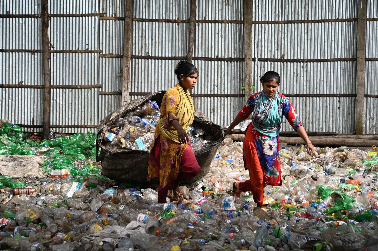 Dua perempuan memilah sampah botol plastik di tempat daur ulang