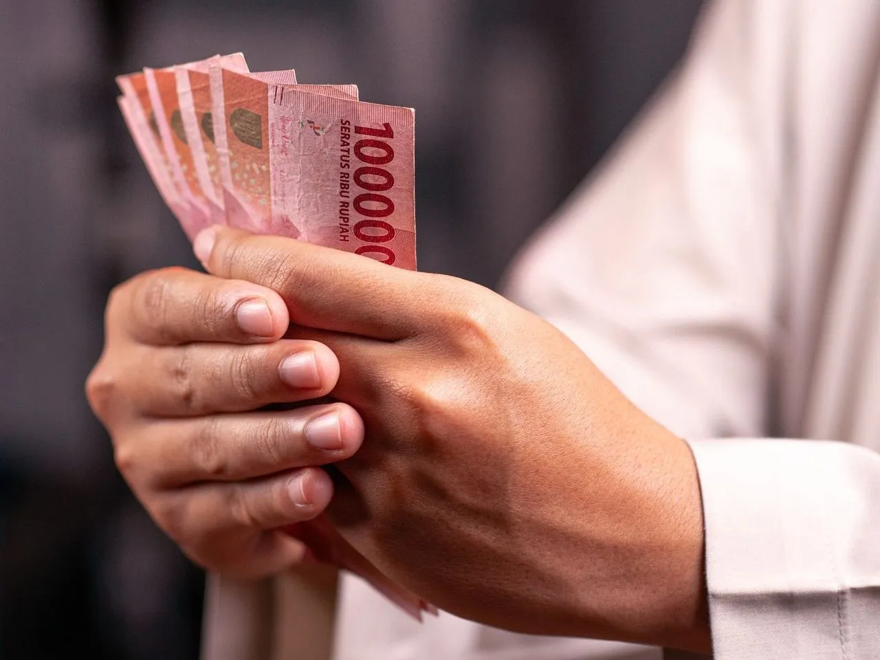 Tangan memegang lembaran uang rupiah