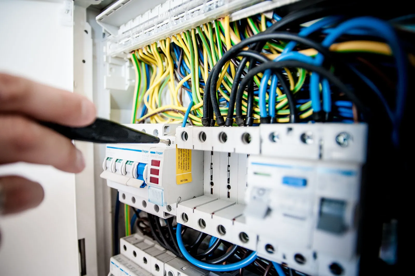 Tangan memeriksa rangkaian kabel di panel listrik