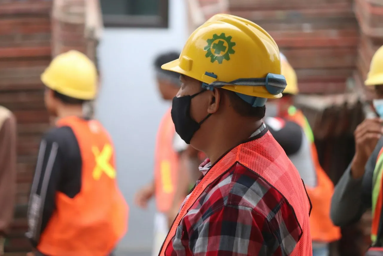 Pekerja berhelm kuning dan rompi keselamatan saat apel kerja