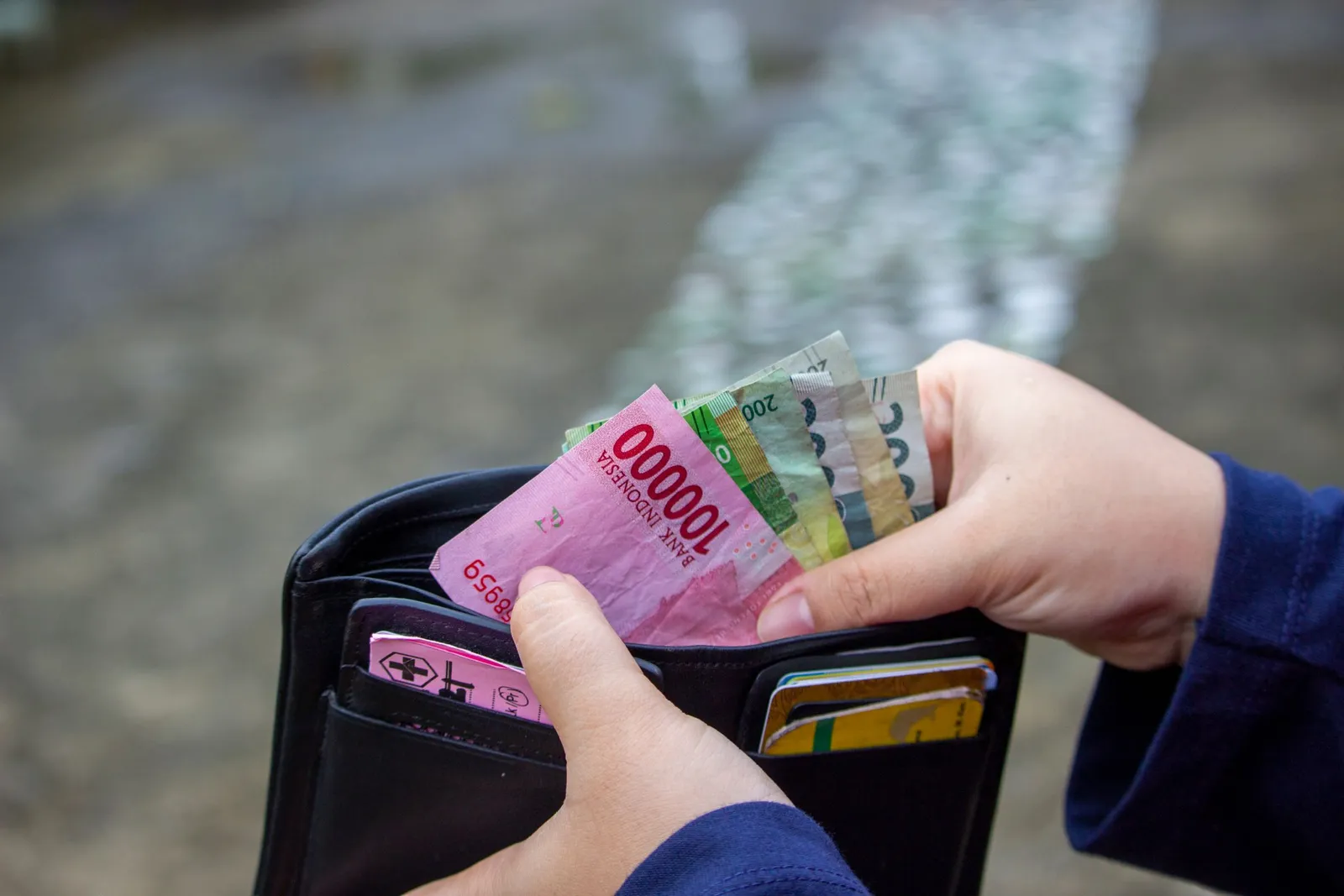 Tangan memasukkan uang rupiah ke dompet