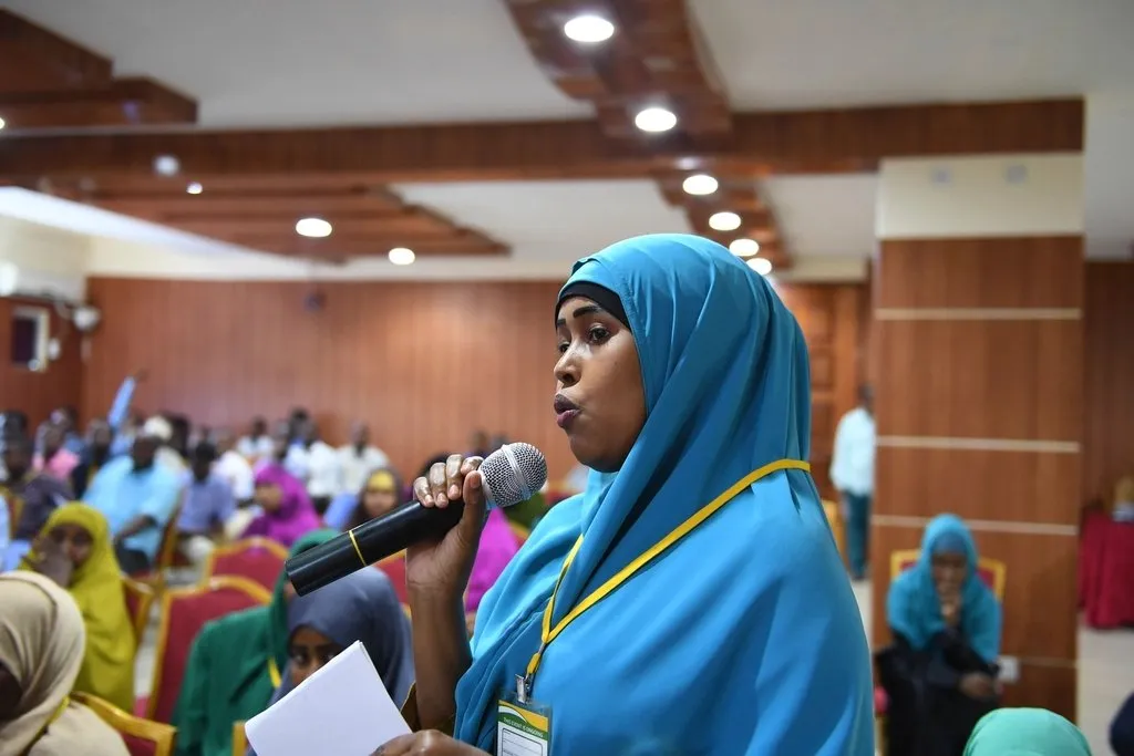 Peserta berhijab bertanya melalui mikrofon di forum diskusi