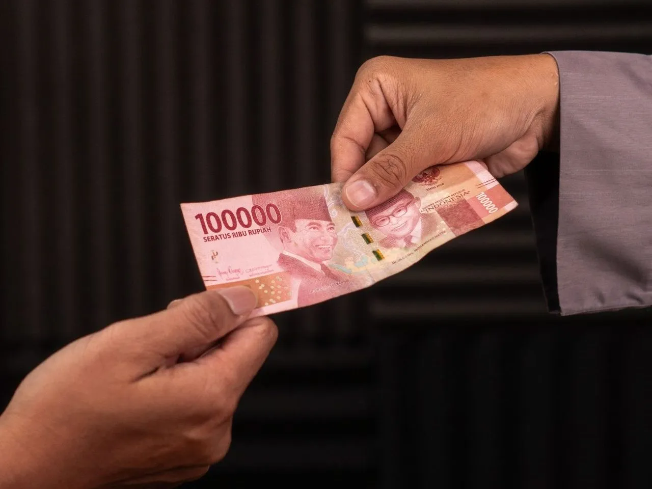 Tangan menyerahkan uang kertas rupiah