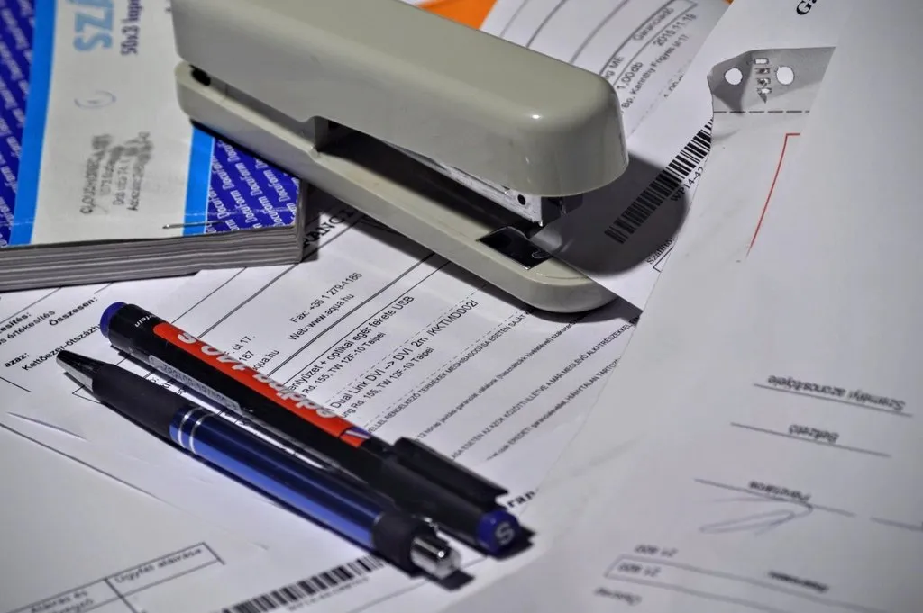 Stapler, pulpen, dan dokumen transaksi di meja