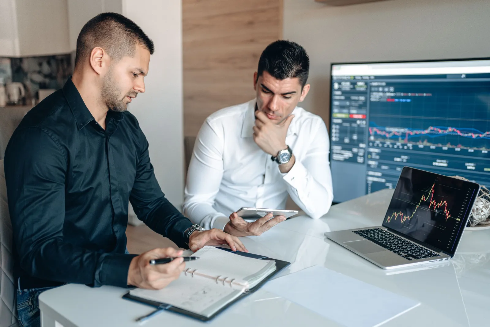 Dua rekan kerja membahas grafik di laptop