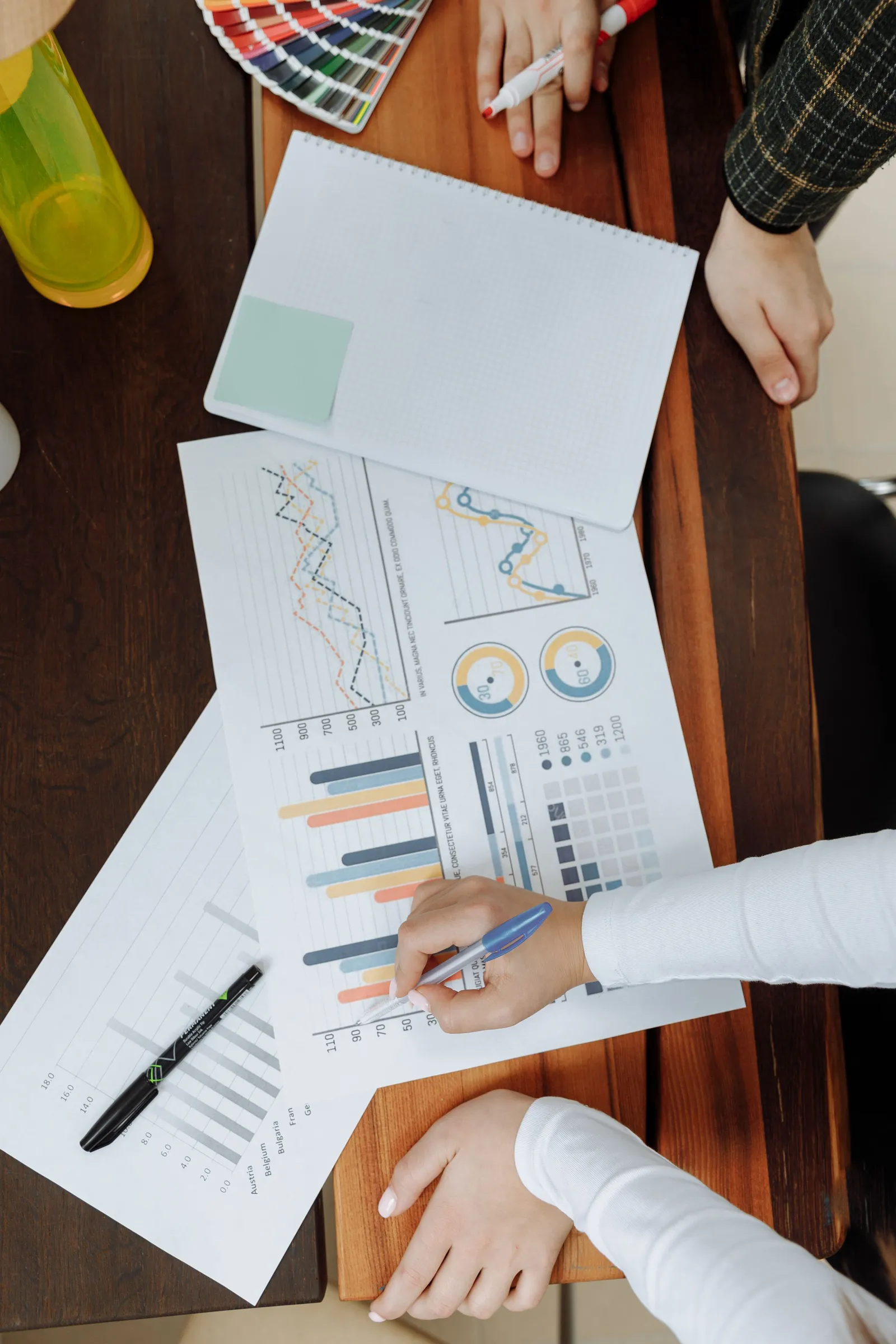Tangan menandai dokumen berisi grafik dan diagram
