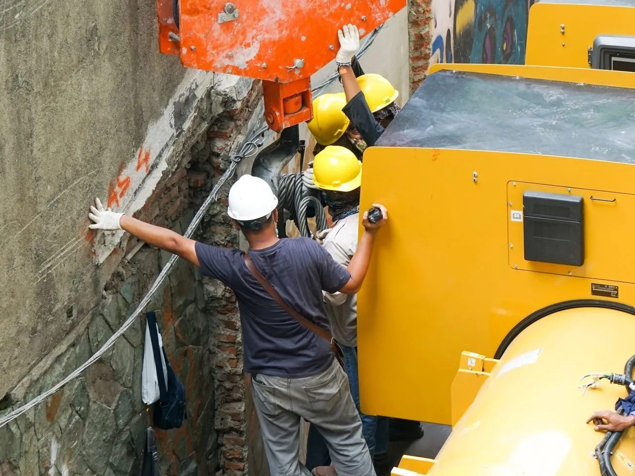 Pekerja berhelm mengoperasikan mesin di lokasi proyek