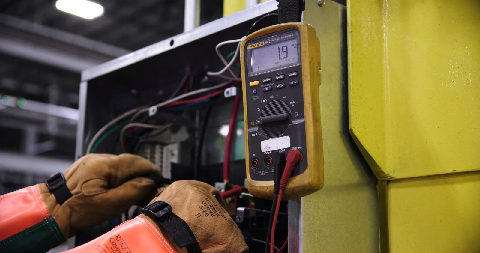 Teknisi mengukur tegangan dengan multimeter