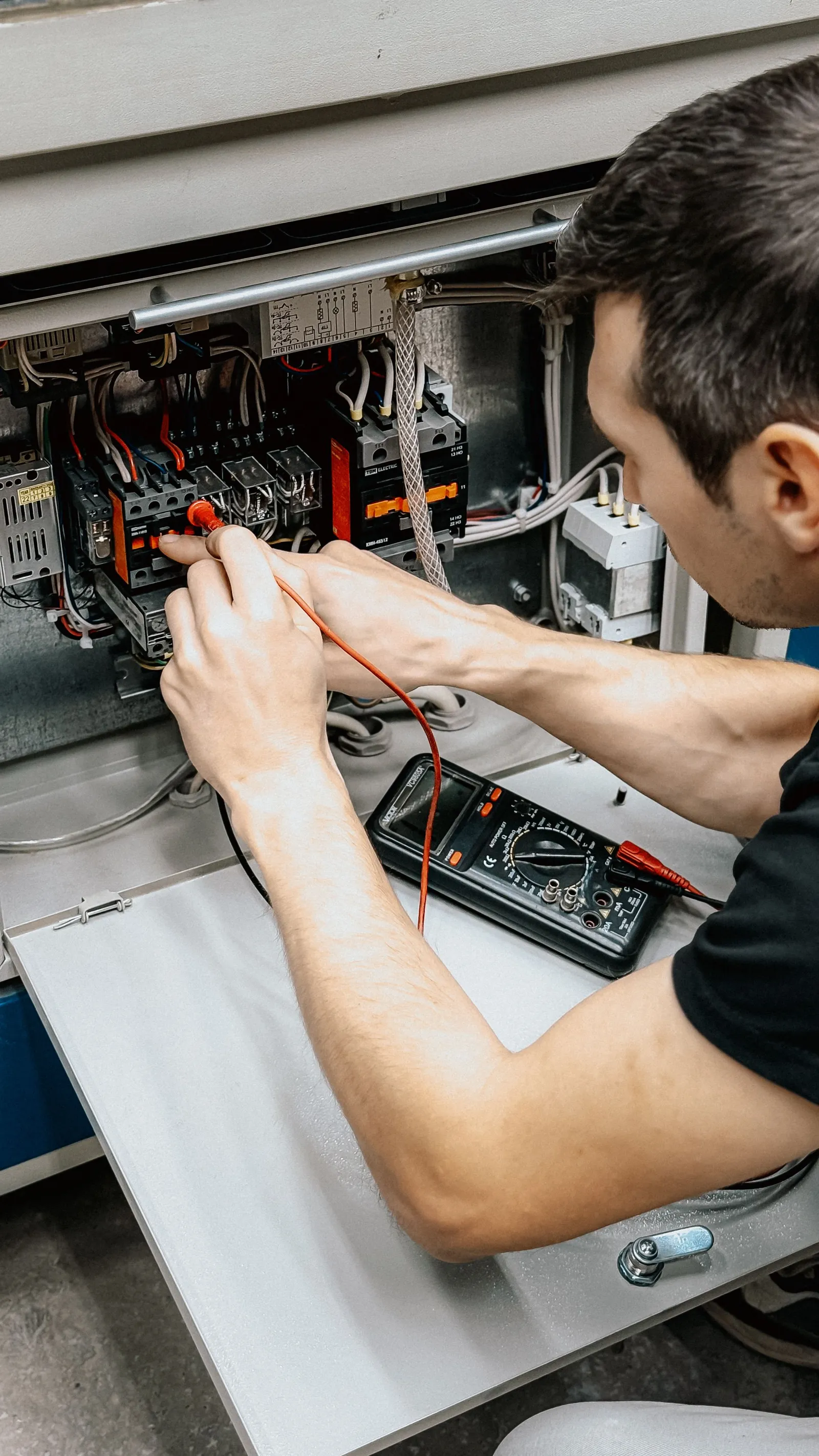 Teknisi mengukur panel listrik dengan multimeter