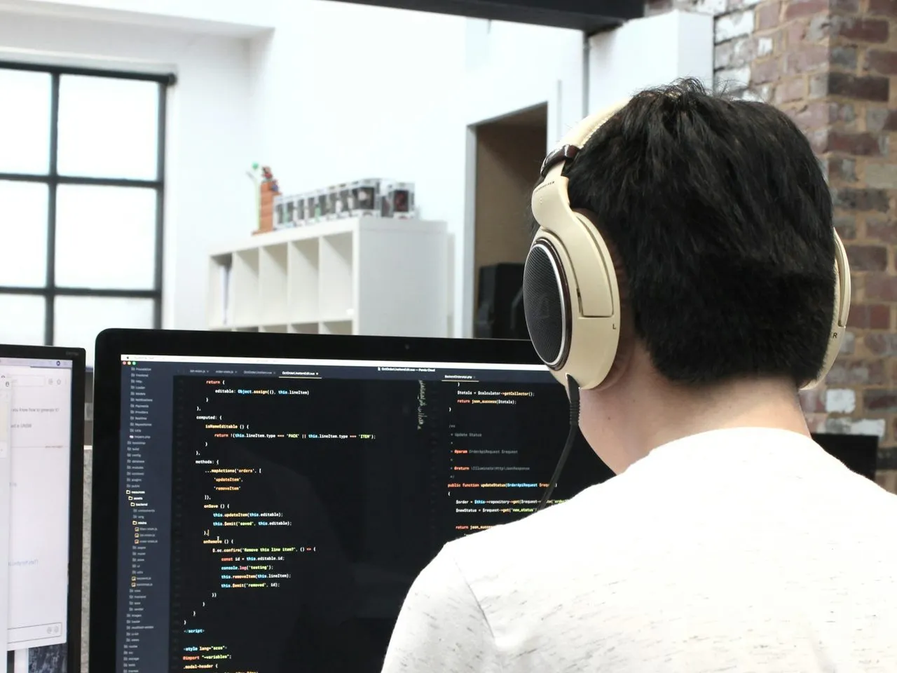 Programmer berheadphone bekerja di depan komputer