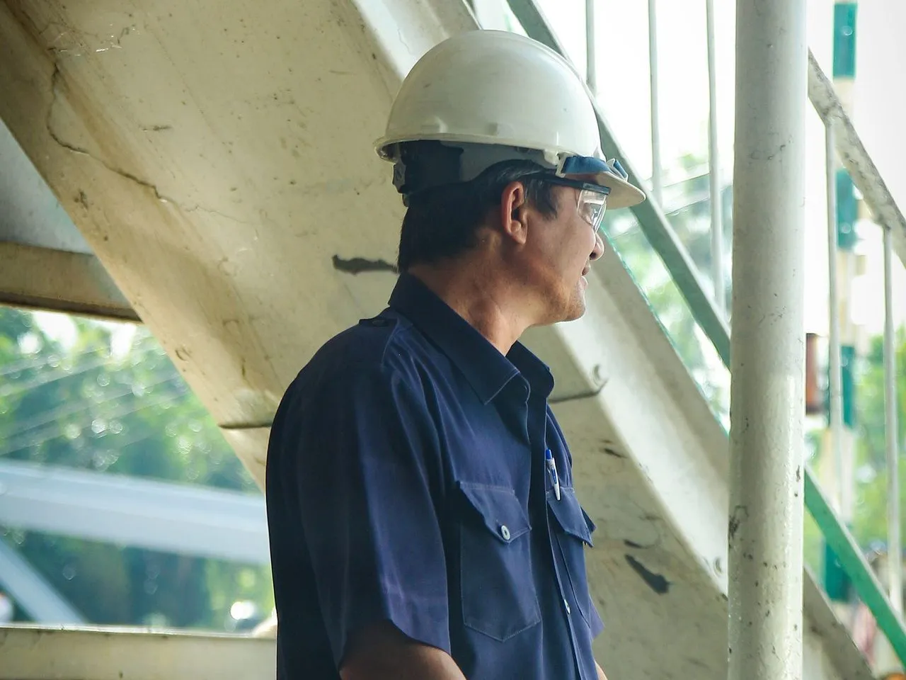 Teknisi berhelm berdiri di tangga fasilitas industri