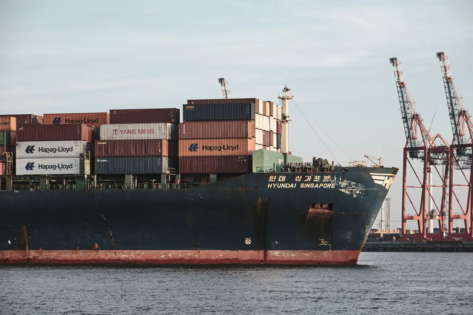 Kapal kontainer bersandar di dermaga dengan derek pelabuhan