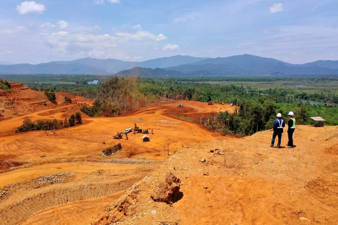 Petugas meninjau area tambang dengan latar pegunungan