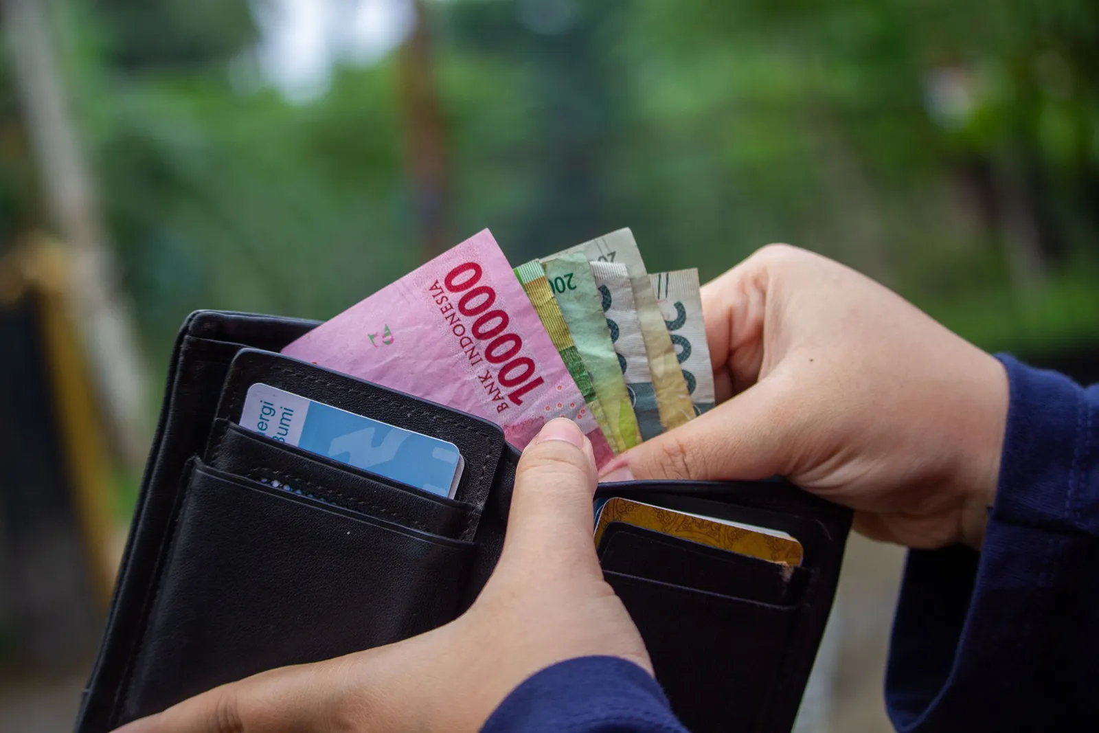 Tangan mengambil uang rupiah dari dompet